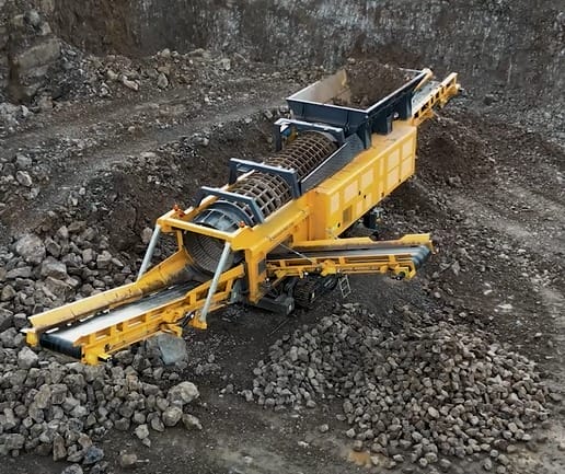 ranoworks A yellow mobile rock crusher machine, alongside powerful screening machinery, processes and sorts rocks and gravel at a quarry site.