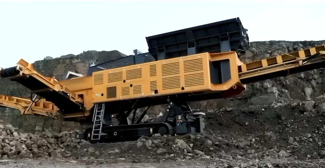 ranoworks A large yellow mobile industrial crusher sits among rocks at a quarry site, with its conveyor extended and a ladder attached for access, showcasing advanced screening machinery.